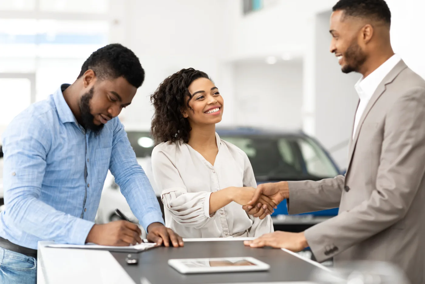 Couple shaking hands with a salesman at a dealership